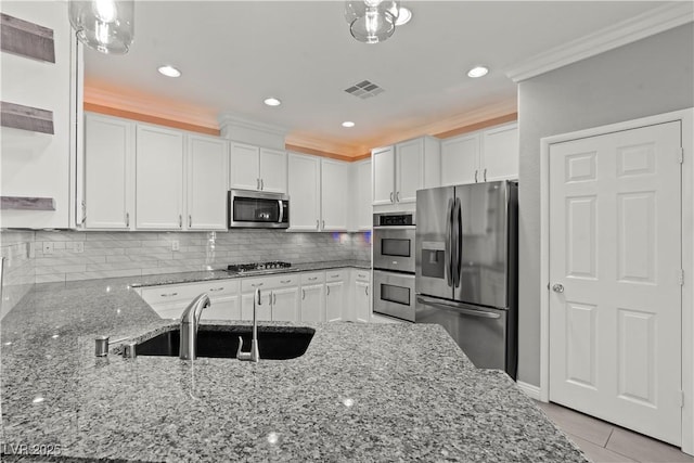 kitchen featuring visible vents, a sink, appliances with stainless steel finishes, white cabinetry, and crown molding