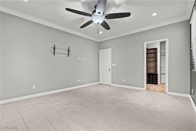 unfurnished bedroom with a walk in closet, a ceiling fan, baseboards, and ornamental molding