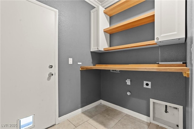 laundry room with electric dryer hookup, baseboards, cabinet space, and light tile patterned floors