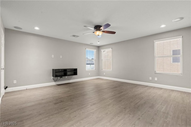 unfurnished living room with a ceiling fan, visible vents, wood finished floors, and baseboards