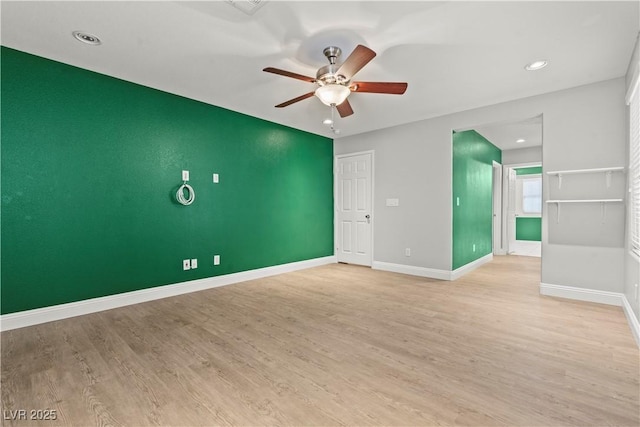 unfurnished room with light wood-type flooring, baseboards, ceiling fan, and an accent wall