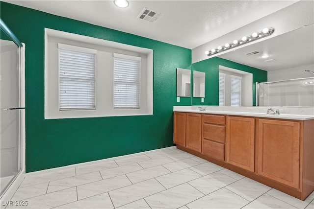 full bathroom featuring double vanity, visible vents, a stall shower, and a sink