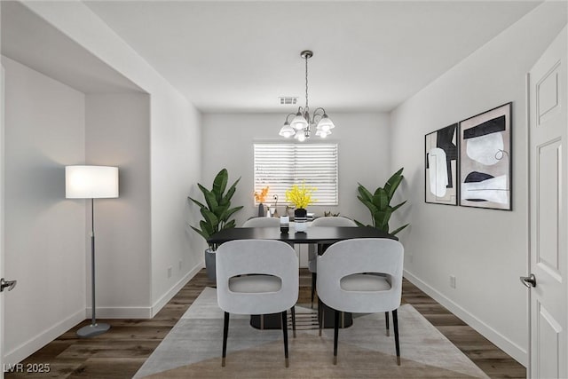 dining space with baseboards, a notable chandelier, and wood finished floors