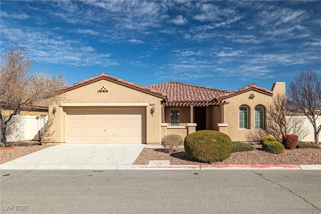 mediterranean / spanish house featuring fence, an attached garage, stucco siding, concrete driveway, and a tile roof