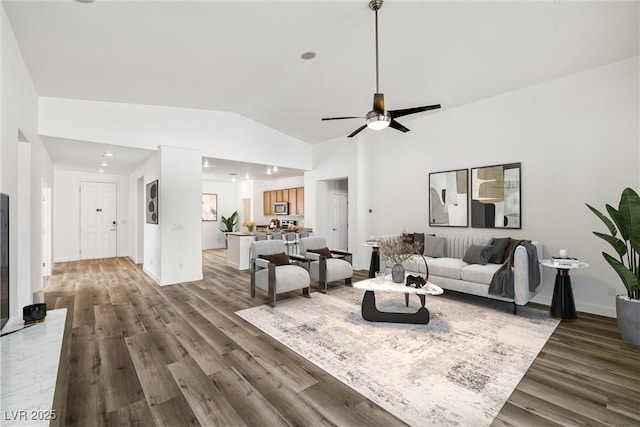 living area featuring ceiling fan, baseboards, lofted ceiling, and wood finished floors