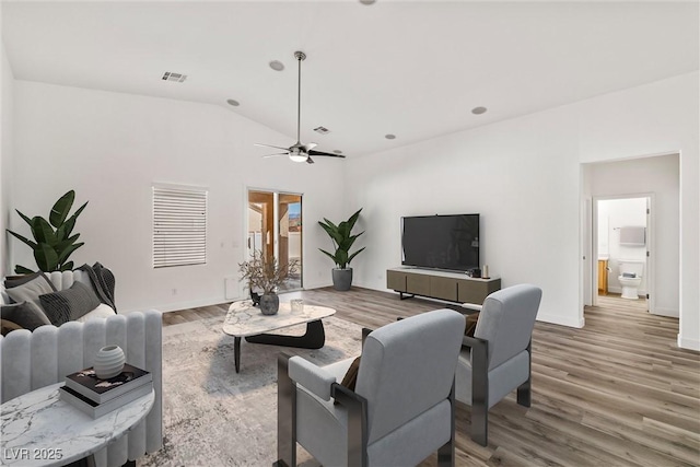 living room featuring visible vents, lofted ceiling, baseboards, and wood finished floors