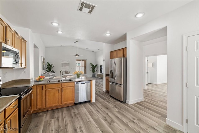 kitchen featuring visible vents, a peninsula, a sink, appliances with stainless steel finishes, and brown cabinets