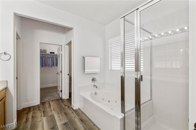 full bathroom featuring vanity, a shower stall, wood finished floors, and a whirlpool tub