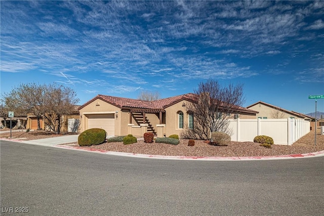 mediterranean / spanish home featuring fence, a tiled roof, stucco siding, a garage, and driveway