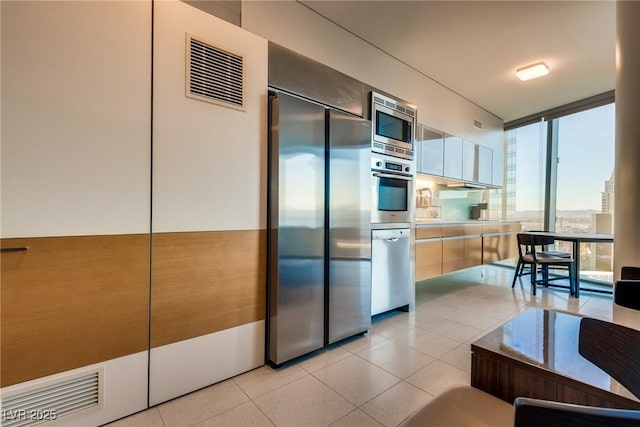 kitchen with built in appliances, light tile patterned flooring, floor to ceiling windows, and light countertops