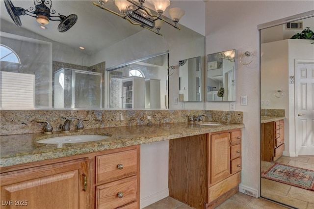 bathroom with double vanity, visible vents, a stall shower, and a sink