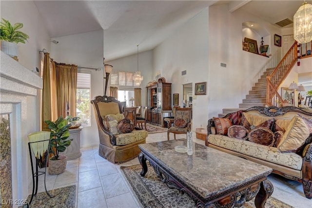 living area with stairway, visible vents, high vaulted ceiling, and an inviting chandelier