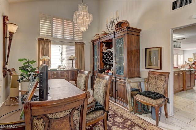 dining room featuring light tile patterned floors, a notable chandelier, visible vents, and a towering ceiling