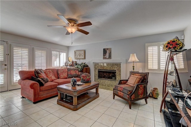 living room with light tile patterned floors, ceiling fan, and a high end fireplace