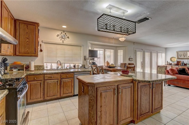 kitchen featuring a sink, appliances with stainless steel finishes, open floor plan, and brown cabinetry