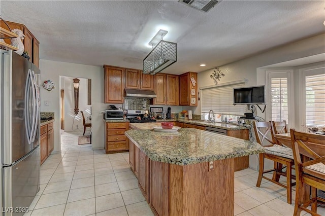 kitchen featuring visible vents, brown cabinets, under cabinet range hood, stainless steel appliances, and light tile patterned floors