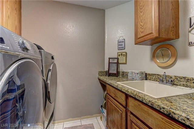 clothes washing area featuring baseboards, light tile patterned floors, washer and dryer, cabinet space, and a sink