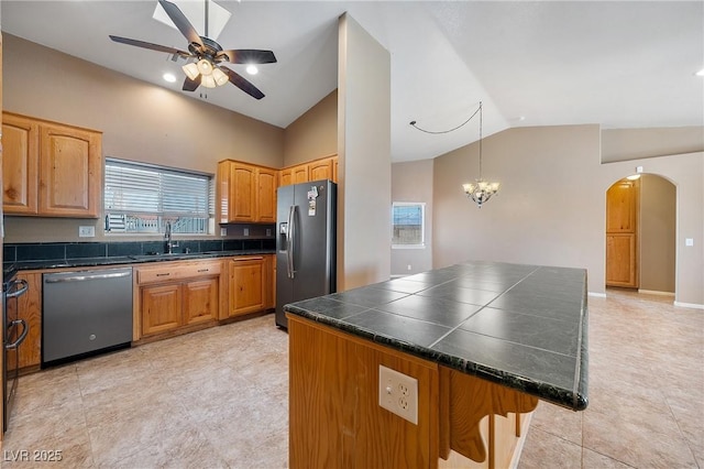 kitchen featuring a kitchen bar, lofted ceiling, arched walkways, stainless steel appliances, and a sink