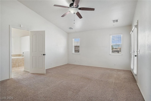 empty room with visible vents, plenty of natural light, light colored carpet, and lofted ceiling