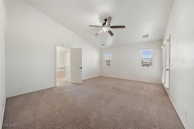 spare room with a ceiling fan, vaulted ceiling, light colored carpet, and visible vents