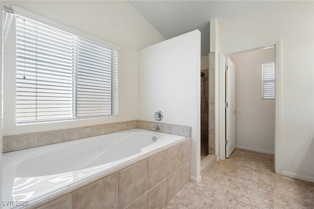 full bathroom featuring a bath, tile patterned floors, a stall shower, and baseboards