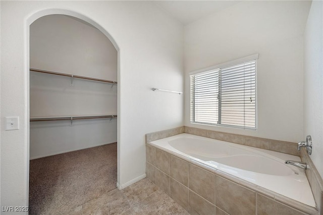 full bathroom featuring a spacious closet and a bath