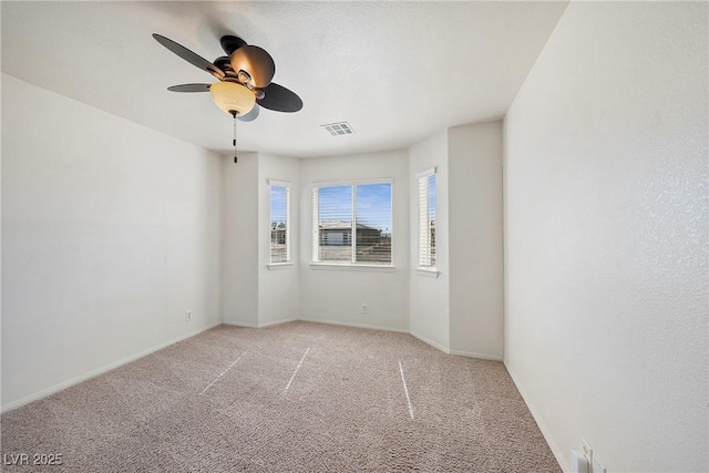 spare room with visible vents, baseboards, light colored carpet, and ceiling fan