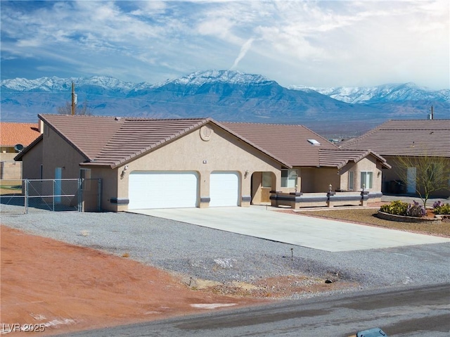 view of front facade with an attached garage, a mountain view, driveway, and stucco siding