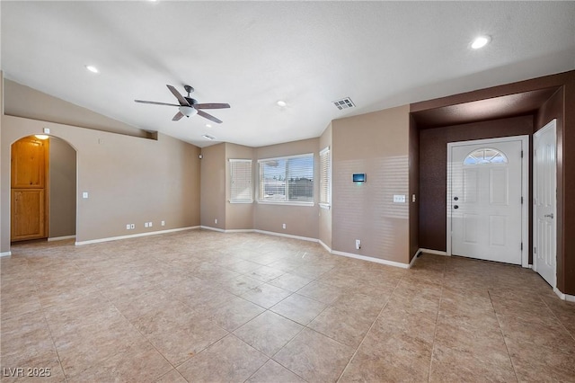 foyer featuring arched walkways, visible vents, baseboards, and vaulted ceiling