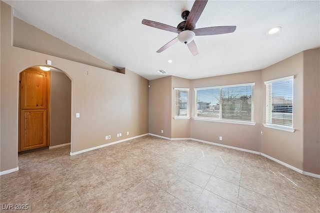 unfurnished room featuring baseboards, arched walkways, visible vents, and vaulted ceiling