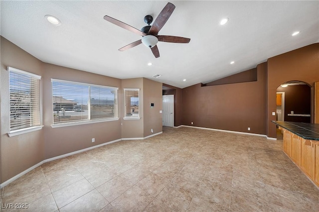 unfurnished living room featuring arched walkways, ceiling fan, baseboards, and lofted ceiling