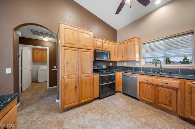 kitchen with washer / dryer, a sink, ceiling fan, vaulted ceiling, and stainless steel appliances