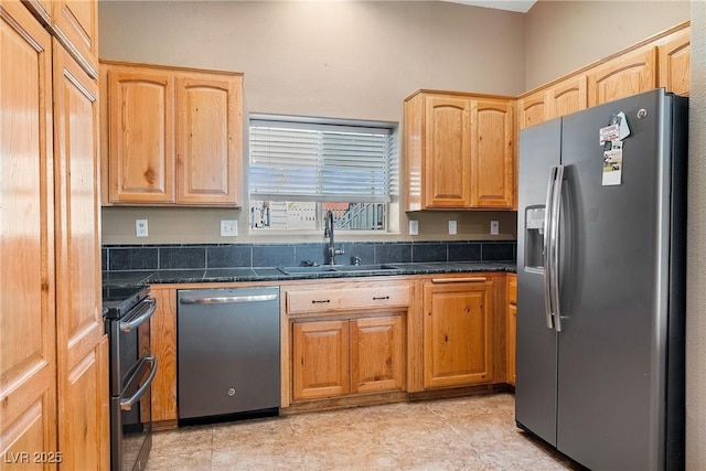 kitchen featuring dark countertops, light brown cabinets, stainless steel appliances, and a sink