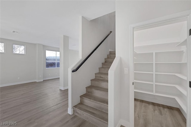 stairs featuring wood finished floors, visible vents, and baseboards