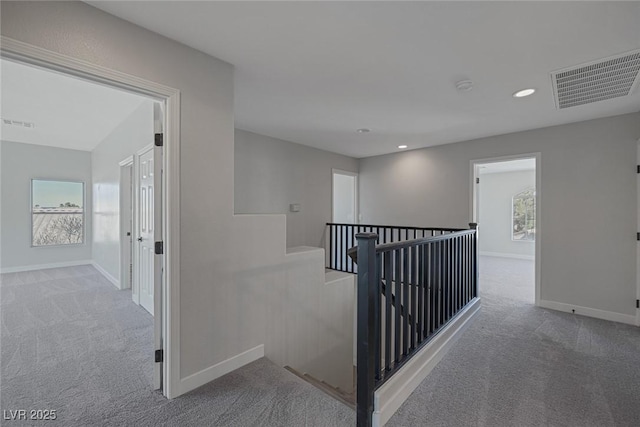 hallway featuring visible vents, an upstairs landing, baseboards, and carpet flooring