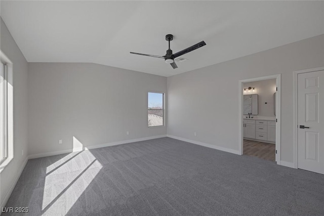 unfurnished bedroom featuring connected bathroom, baseboards, ceiling fan, lofted ceiling, and carpet flooring