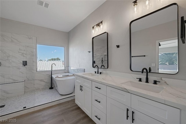 bathroom with visible vents, wood finished floors, walk in shower, and a sink