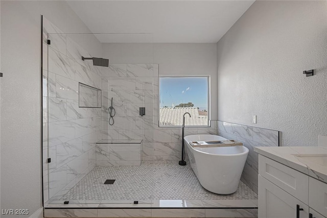 full bathroom with vanity, a soaking tub, a stall shower, tile walls, and a textured wall