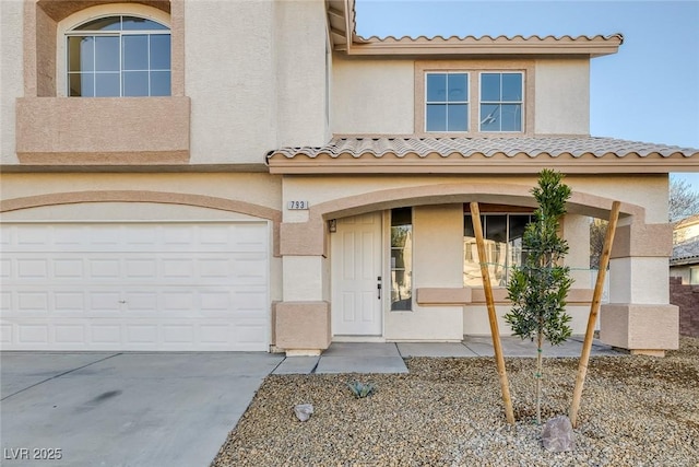 view of front of home featuring concrete driveway, a tiled roof, and stucco siding