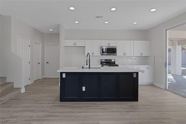 kitchen featuring visible vents, a sink, appliances with stainless steel finishes, white cabinets, and light countertops