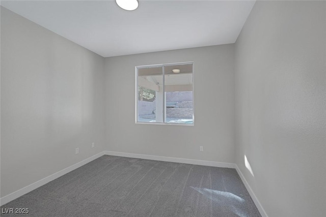 empty room featuring baseboards and dark carpet