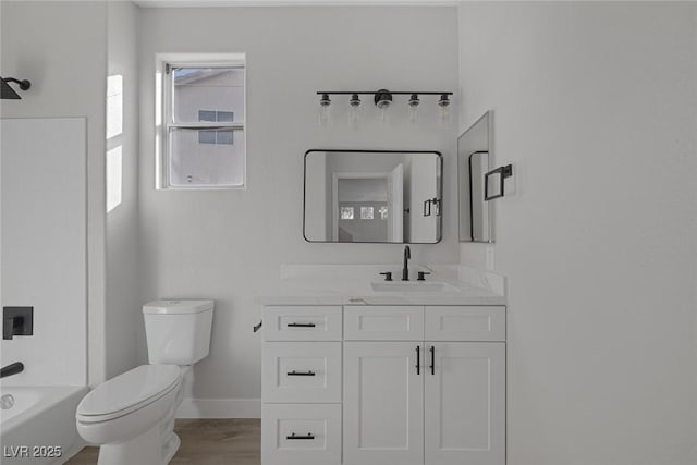 bathroom featuring toilet, vanity, baseboards, and wood finished floors