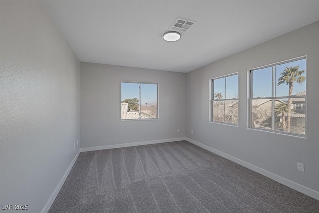 empty room featuring visible vents, baseboards, and dark carpet