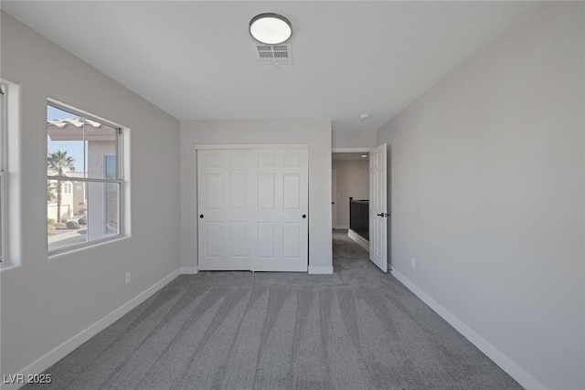 unfurnished bedroom featuring visible vents, baseboards, carpet, and a closet