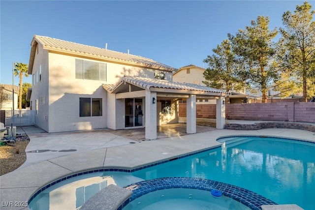 back of house featuring a tiled roof, a pool with connected hot tub, a fenced backyard, and a patio