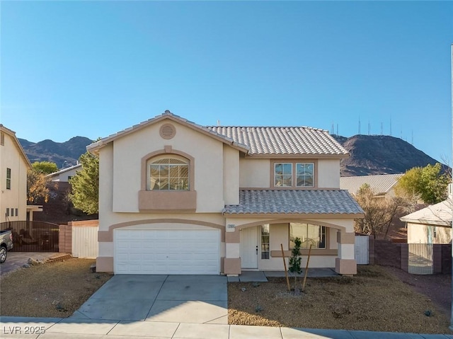 mediterranean / spanish-style home with concrete driveway, a tiled roof, a gate, and stucco siding