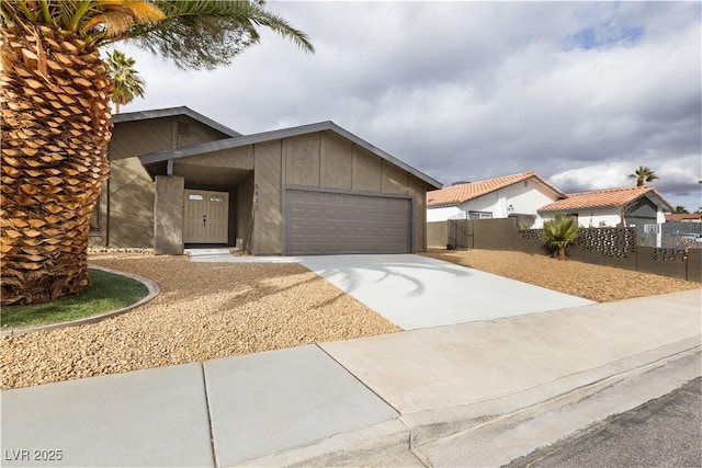 view of front of home featuring driveway, board and batten siding, an attached garage, and fence