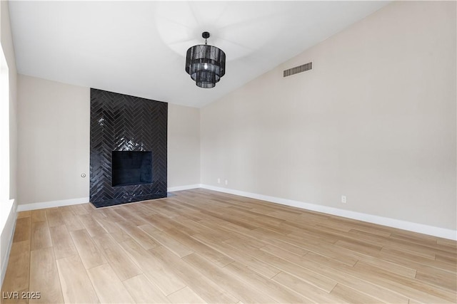 unfurnished living room featuring light wood-style floors, a fireplace, visible vents, and baseboards