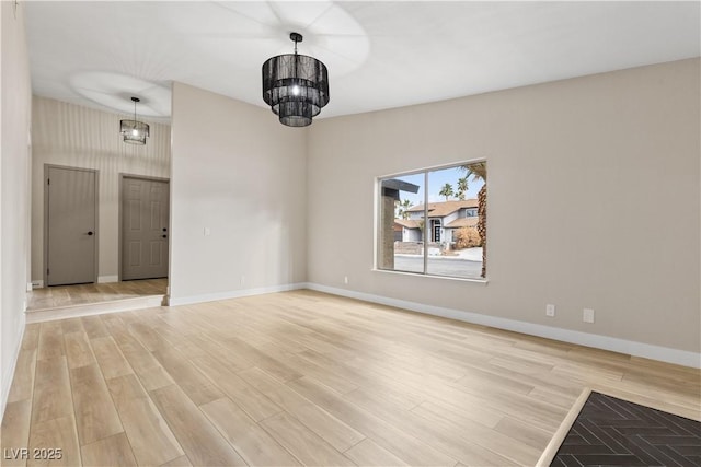 unfurnished dining area with light wood-style flooring, baseboards, and an inviting chandelier