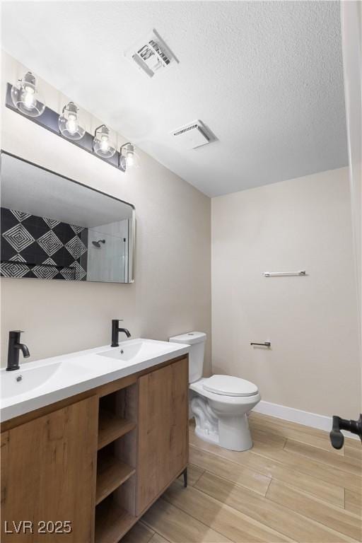 bathroom with double vanity, toilet, wood finished floors, and visible vents